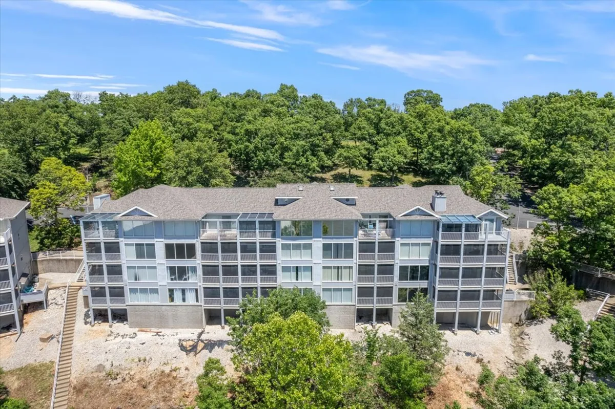 A modern exterior with expansive glass windows, surrounded by greenery and natural landscaping. The design blends indoor and outdoor living, offering balconies perfect for sunset watching and wildlife observation in a calm, secure environment.